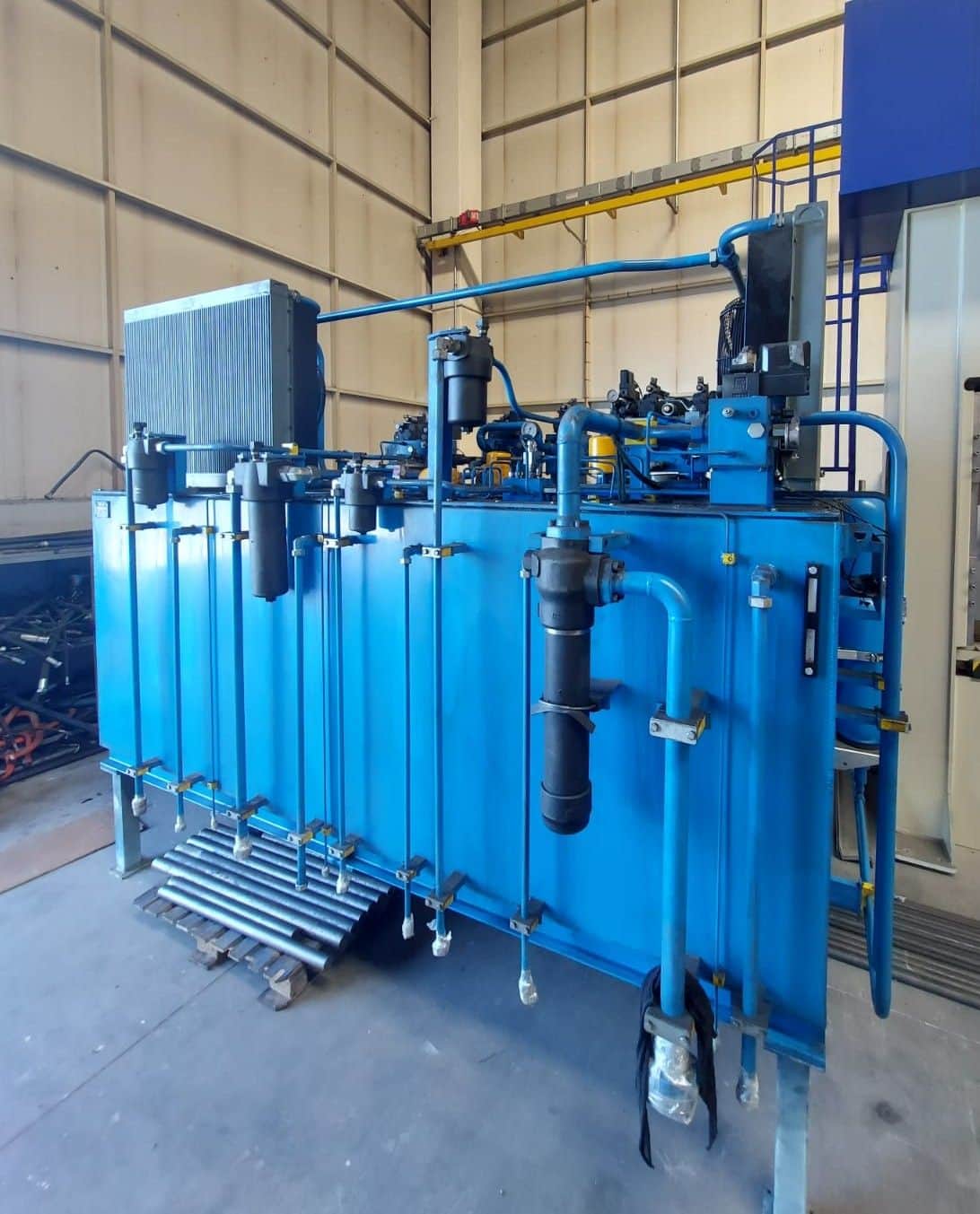 Industrial hydraulic power unit assembled at the AEB Engineering workshop — high-capacity blue tank, side-connected piping assembly, and top-mounted filter group