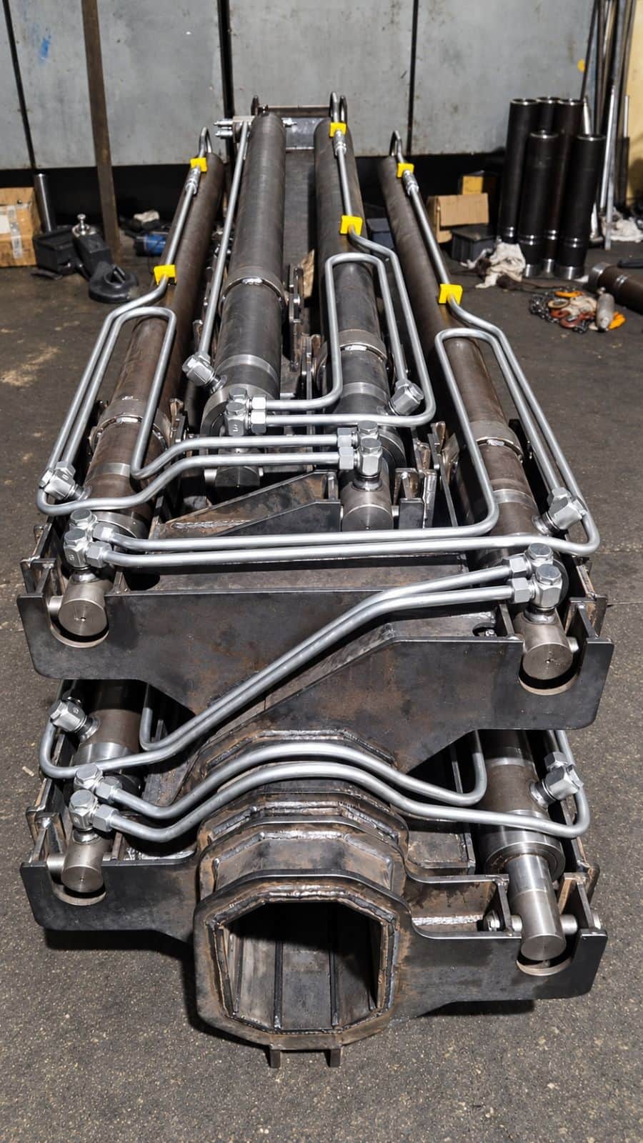 Hydraulic cylinders integrated into mobile crane boom mechanism — custom bent steel piping installation and compact hydraulic line assembly by AEB Engineering